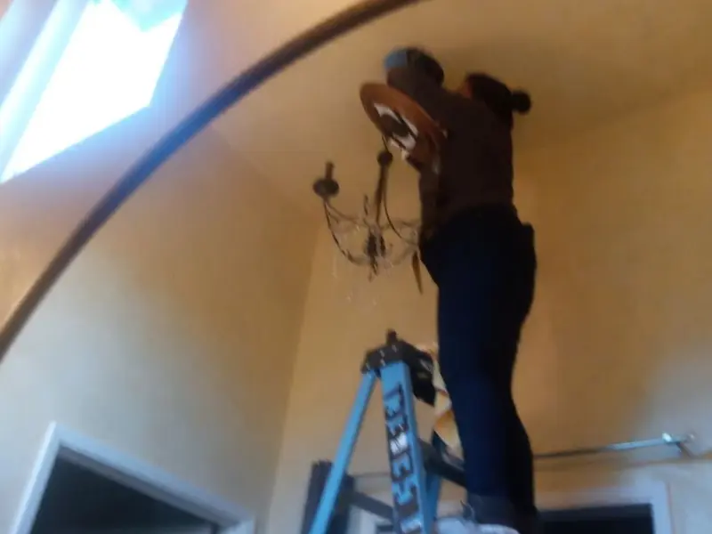 Electrician installing a chandelier in a Clarksdale residence
